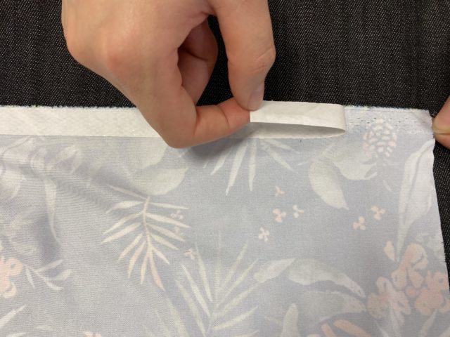 Peel-off-paper-backing-of-hotmelt-net-adhesive-on-lycra-textile